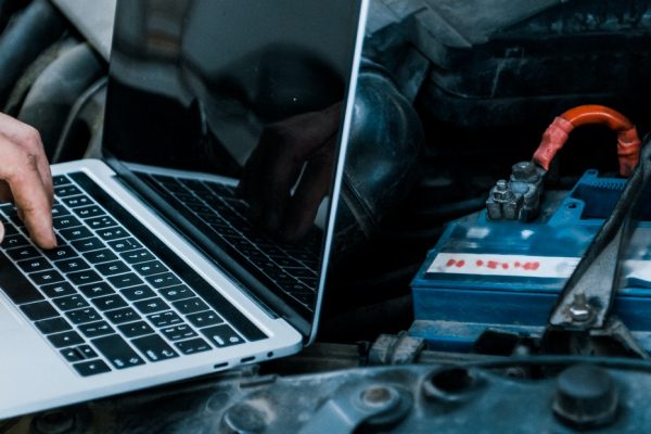 panoramic shot of car mechanic using laptop with blank screen near car panoramic shot of car mechanic using laptop with blank screen near car